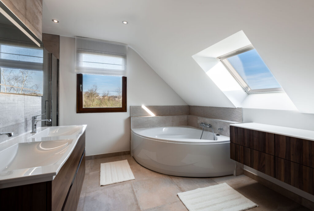 Salle de bain moderne avec une baignoire d'angle, un meuble vasque en bois, et une grande fenêtre de toit.